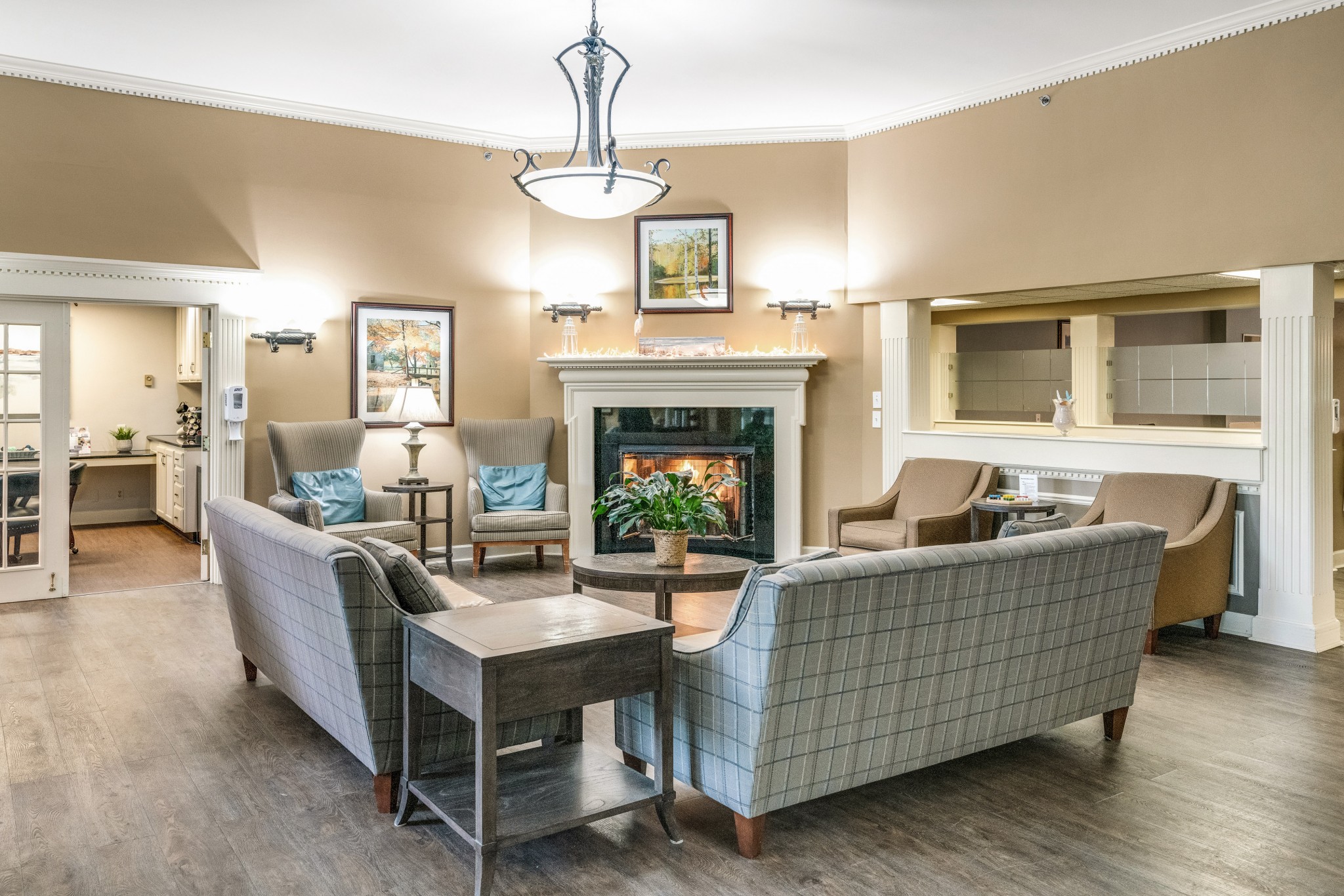 A sitting area with a fireplace and a painting above it, gray couches and sofa chairs, surrounding the fireplace at Shorehaven, a senior living community near Washington Township.