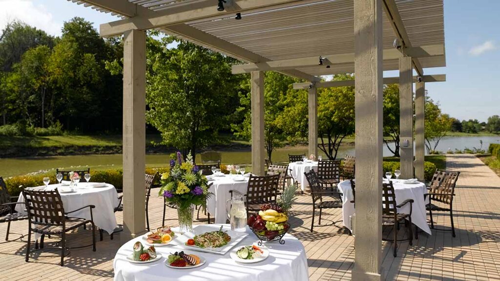 atria-shorehaven-03 - Shorehaven A patio set under a shaded pergola with a beautiful lake backdrop at Shorehaven, a top choice for senior living near Warren.